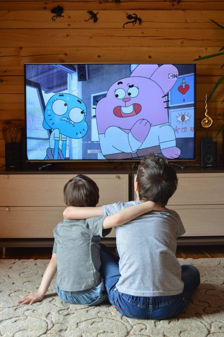 Siblings watching TV in entertainment room