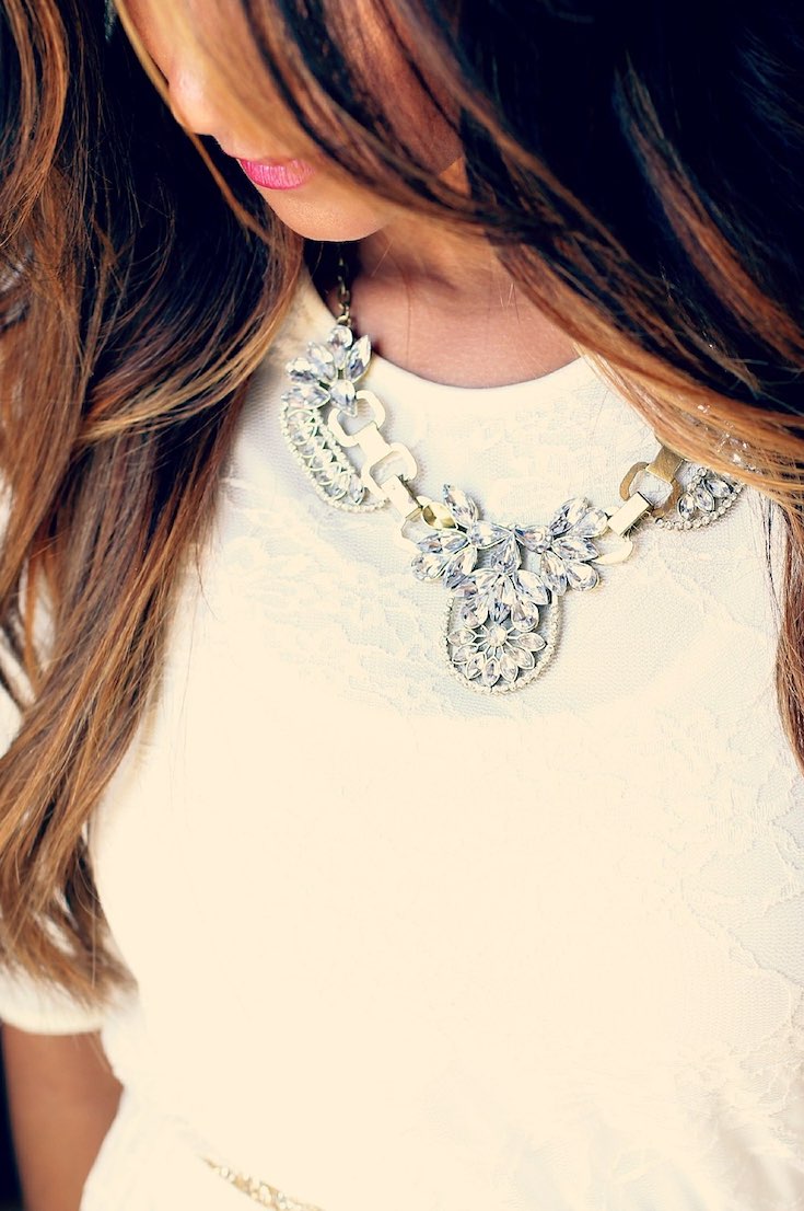 Woman wearing cocktail necklace on white top