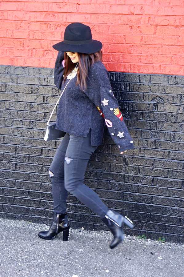Patched navy sweater, skinny jeans and a black hat and boots