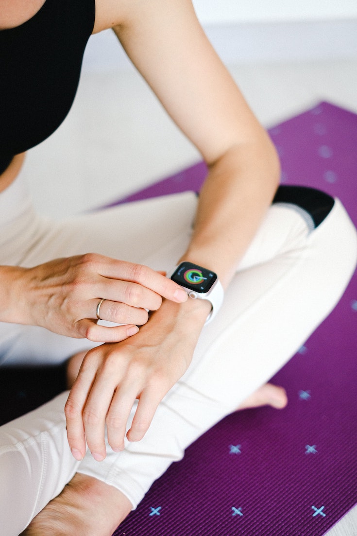 Woman sitting and looking at her fitness tracker, workout plan for the new year