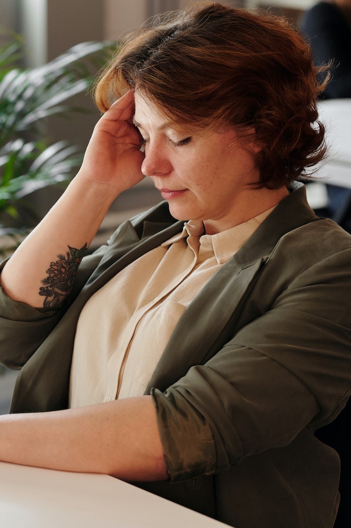 Woman sitting with hand on head with a headache