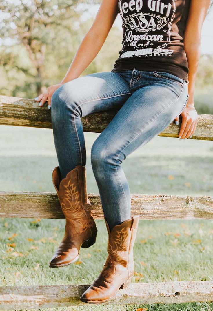 Woman wearing cowboy boots jeans and a top